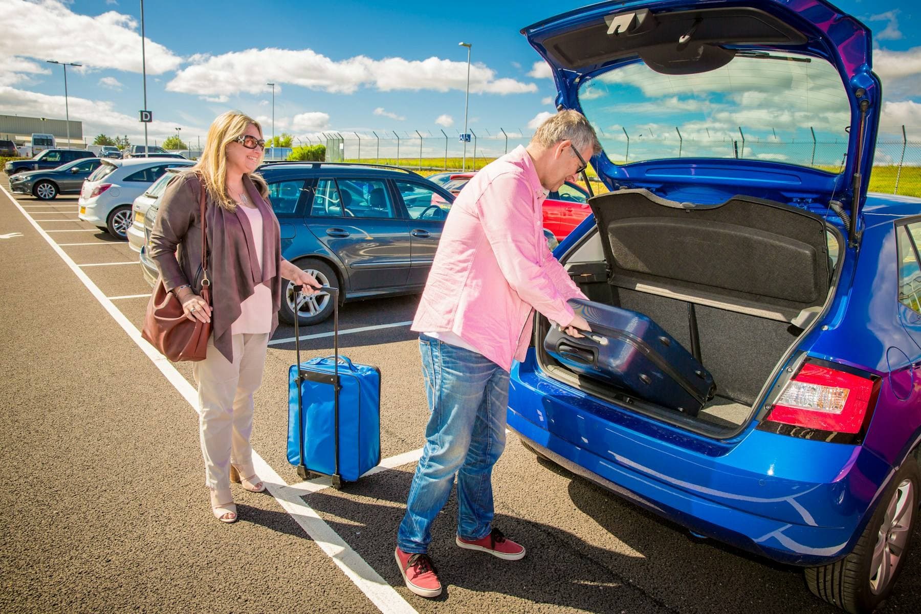 Stel laadt een koffer in de achterbak van hun auto