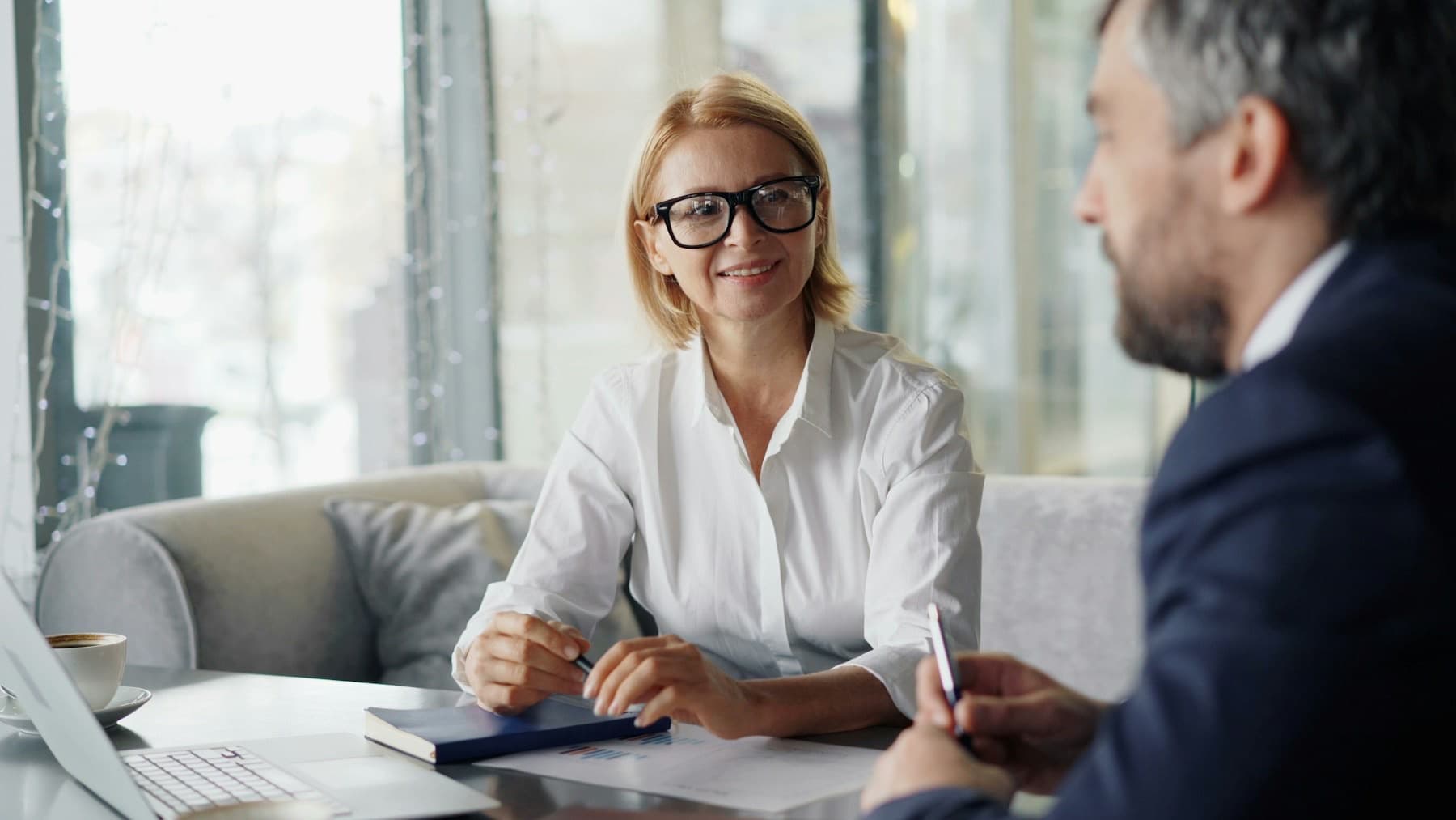 Vrouw bespreekt documenten met een adviseur aan tafel